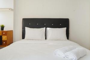 - un lit avec des oreillers blancs et 2 serviettes dans l'établissement Homey Studio Apartment at Margonda Residence 3 By Travelio, à Depok