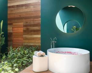 a bathroom with a white tub and a mirror at SALA Samui Chaweng Beach Resort in Chaweng