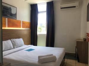 een slaapkamer met een wit bed en een raam bij Place2Stay @ Kenyalang in Kuching