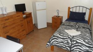 a bedroom with a bed and a dresser and a television at Star Inn Accommodation in Mount Isa