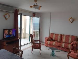 ein Wohnzimmer mit einem Sofa, einem TV und einem Tisch in der Unterkunft Monaco Sunset T3 avec garage Vue imprenable in Beausoleil