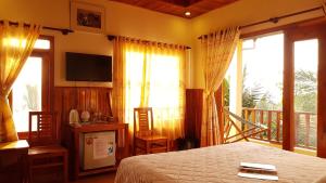 a bedroom with a bed and a balcony with windows at Free Beach Resort in Phú Quốc