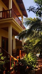 a house with a balcony and a palm tree at Free Beach Resort in Phú Quốc