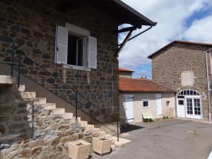 a stone building with stairs next to a building with a window at Domaine des Gardette in Vaux-en-Beaujolais