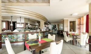 a dining room with a table and white chairs at Hunguest Hotel Apollo in Hajdúszoboszló