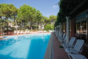 a large swimming pool with lounge chairs and trees at Hotel Meeting in Cesenatico