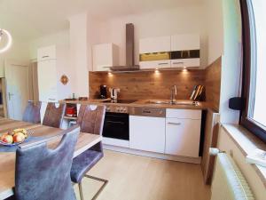 a kitchen with white cabinets and a table and a sink at Ferienwohnung Albstadt Panorama in Albstadt