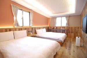 two beds in a room with two windows at MountainTraveler in Renai