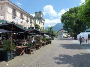 a group of people sitting at tables in a street at Casa Rana in Ascona