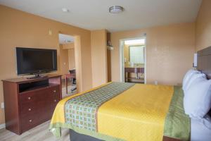 a hotel room with a bed and a flat screen tv at The Crossroads Hotel and Suites Irving in Irving