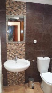 W łazience znajduje się umywalka, toaleta i lustro. w obiekcie Casa do carmo N 10 w mieście Olhão