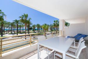 una mesa blanca y sillas en un balcón con palmeras en UHC Novelty Apartments, en Salou