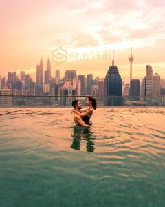 Ein Mann und eine Frau sitzen im Wasser der Stadt in der Unterkunft Regalia Residence The Sky Pool Suite in Kuala Lumpur