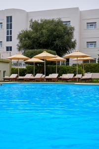 a large swimming pool with chairs and umbrellas at Civitel Esprit in Athens