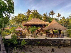 a restaurant with tables and chairs and umbrellas at Ceningan Resort in Nusa Lembongan