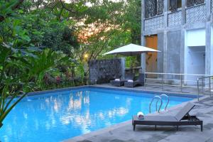 a swimming pool with a bench and an umbrella at Oak Tree Emerald Semarang Managed by The Ascott Limited in Semarang