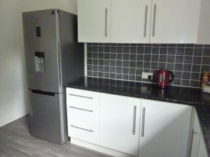 a kitchen with white cabinets and a stainless steel refrigerator at Paisley Central Apartment #4 in Paisley +10 photos