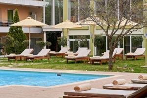 uma piscina com espreguiçadeiras e guarda-sóis ao lado de um edifício em Civitel Attik Rooms & Suites em Atenas