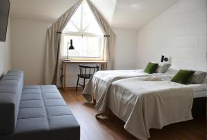 a bedroom with two beds and a couch and a window at HeseHotelli Turku Kaskentie in Turku