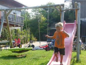 Ein kleiner Junge, der auf einer Rutsche im Garten spielt in der Unterkunft Familienferienhof Stabauer in Zell am Moos