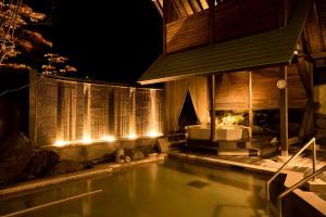 a swimming pool next to a house at night at Kusatsu Onsen Hotel Village in Kusatsu