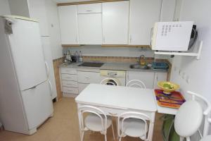 kuchnia z białymi szafkami i białą lodówką w obiekcie AR1B, Acogedor estudio a pie de playa w mieście Villajoyosa