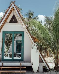 a surfboard leaning against a house on the beach at Mao Mao surf in General Luna