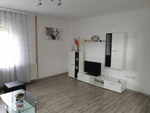 a white living room with a tv and a glass table at Apartman Majetić in Otočac