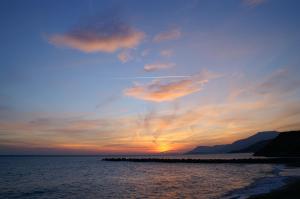 a sunset over the ocean with a rocky pier at Sole Mare in Ventimiglia