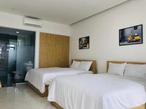 2 bedden in een hotelkamer met witte lakens bij The Stay Apartment Pleiku in Pleiku