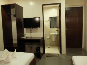 a bedroom with a bathroom with a television and a desk at Casa Coron Hotel in Coron