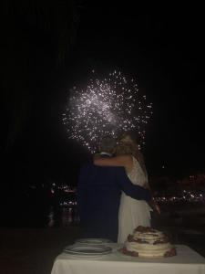 una novia y un novio parados frente a una mesa con fuegos artificiales en Villa Rossa en Parga