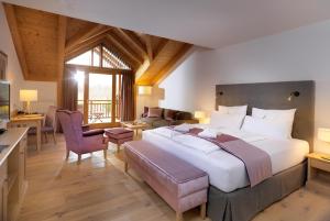 una camera con un grande letto e un soggiorno di Dolomitengolf Hotel & Spa a Lavant