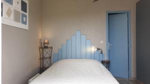 een slaapkamer met een bed met een blauwe muur bij Gîte A l'ombre du clocher in Calenzana
