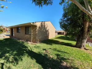 a brick house with a tree in the yard at Ocean Beach Chalet 15 in Jurien Bay