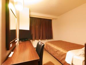 熊本市にある熊本グリーンホテルのベッドとデスクが備わるホテルルームです。
