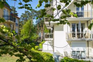 a white building with a balcony and trees at Ferienappartement Sonnenreich in Baabe