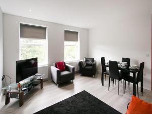 sala de estar con mesa, sillas y TV en Queens Quarter Apartments en Belfast
