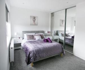 a bedroom with a large bed and a mirror at Queens Quarter Apartments in Belfast