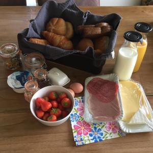 una mesa con un tazón de fresas y una cesta de pan en Speldehof, en Kraggenburg