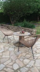 2 chaises et une table sur une terrasse en pierre dans l'établissement Jo Masson, à Saint-Aubin-dʼAubigné