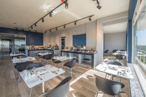 a restaurant with white tables and black chairs at Glam Hotel Nairobi - Near Westgate Mall, Westlands in Nairobi