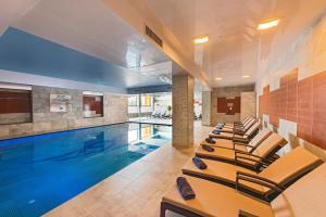 a pool with a row of chairs next to a swimming pool at Grand Hotel Gozo in Għajnsielem