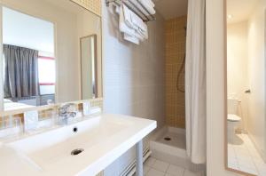 bagno bianco con lavandino e specchio di Orly Superior Hotel ad Athis-Mons