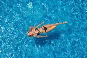 a woman swimming in a pool of blue water at Boton Blue Hotel & Spa in Nha Trang