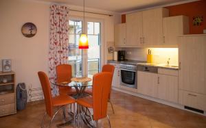 a kitchen with a glass table and orange chairs at Ferienappartement Sonnenreich in Baabe