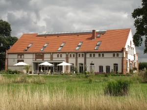 un grand bâtiment blanc avec un toit rouge dans l'établissement Landhaus Ribbeck, à Ribbeck