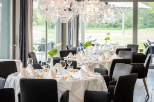 a dining room with tables and chairs and chandeliers at Dolomitengolf Suites in Lavant