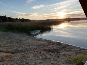 a boat sitting on the shore of a body of water at Dom na Mazurach LUNA HAUS in Ełk