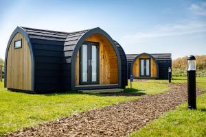 zwei kleine Cottages auf einem Feld mit Gras in der Unterkunft Camping Pods, Golden Sands Holiday Park in Dawlish